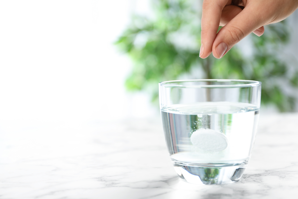 Womans hand, tablet dissolving in glass